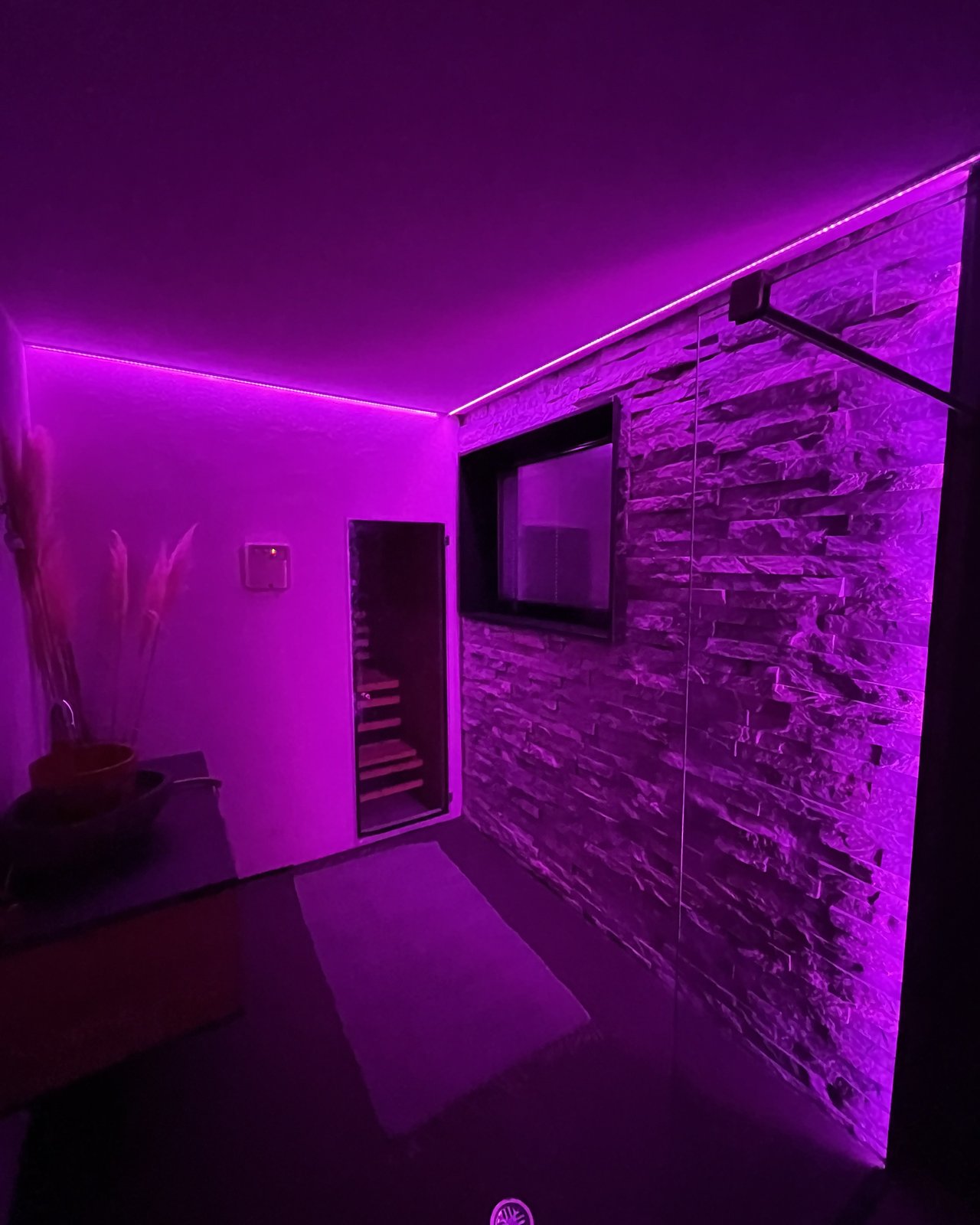 Badezimmer mit Natursteinwand, begehbarer Dusche und Waschtisch