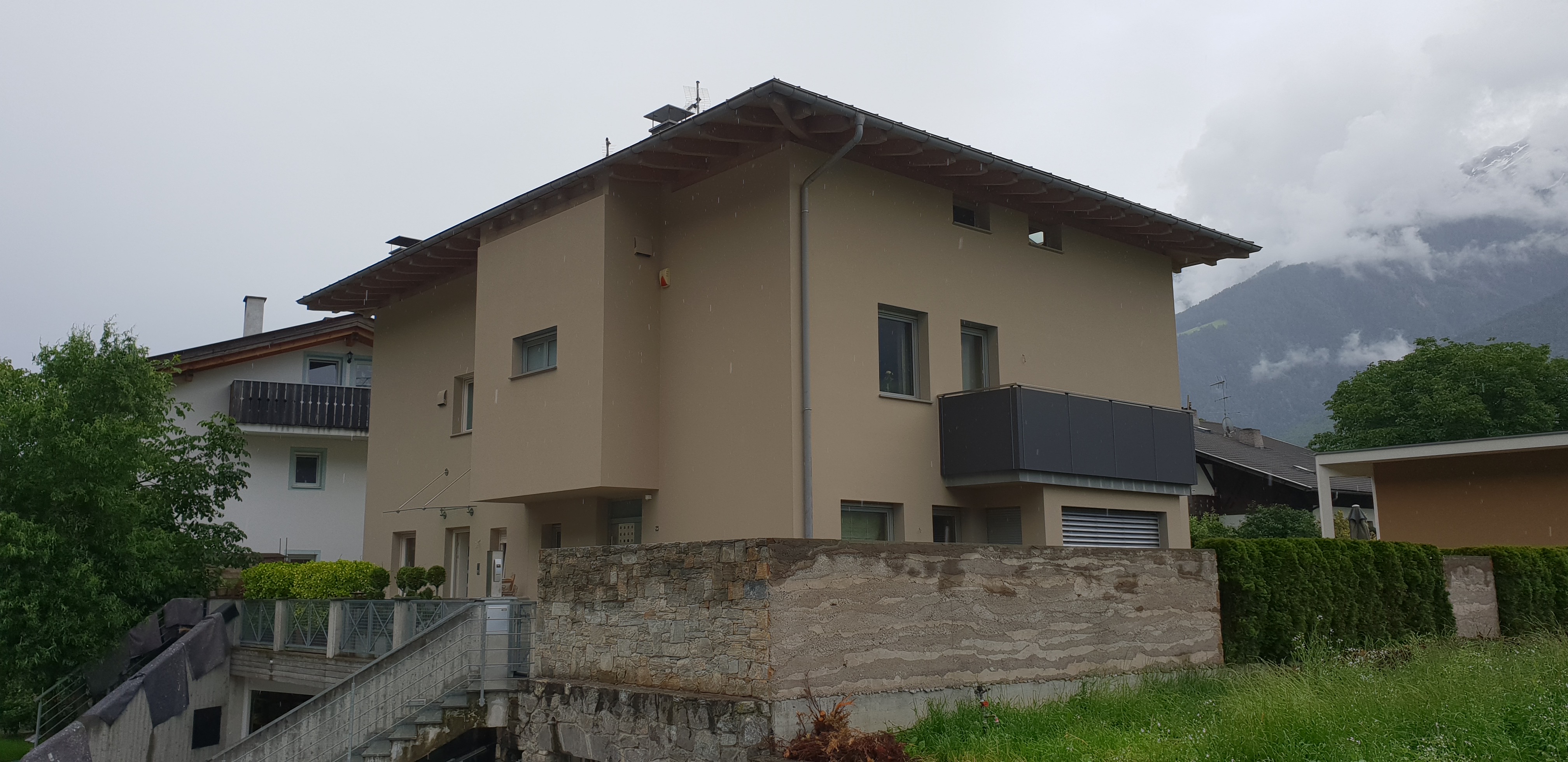 Wohnhaus mit beiger Fassade und dunkel abgesetztem Balkon